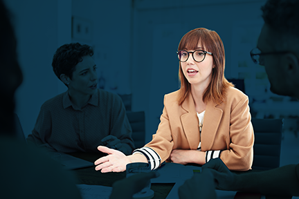 Young woman safety professional with glasses and a brown jacket managing a conflict between coworkers in a conference room 