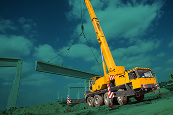 A mobile crane on a construction job site with a blue background